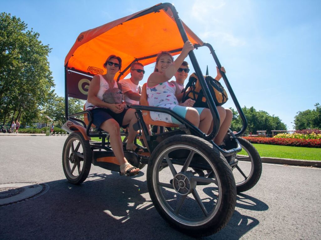 család vidáman bringóhintózik a napsütésben