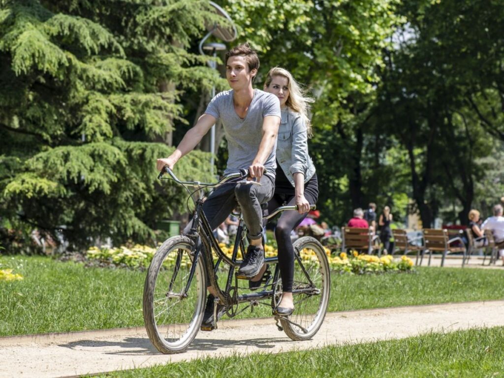 egy pár tandem biciklin teker a napsütésben